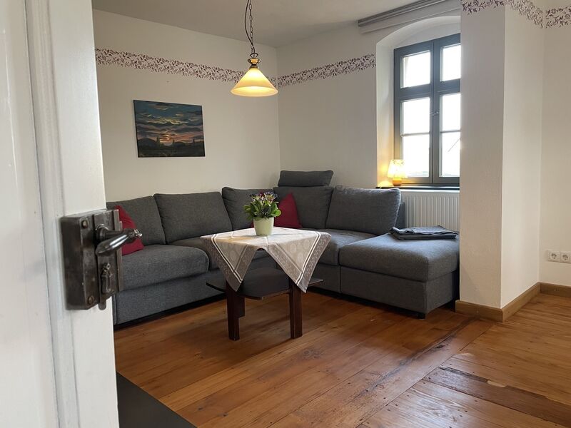 Blick von der Wohnzimmertür auf die Eckcouch mit kleinem Tisch.